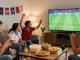 Excited fans watching a live match on موقع IHD Sports, snacks and team flags enhance the vibrant atmosphere.