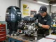 Expert outboard motor repair showing Yamaha engine disassembly in a busy workshop.
